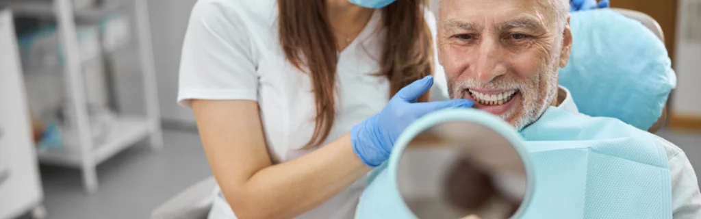 Patient looks into the small mirror after dental implants